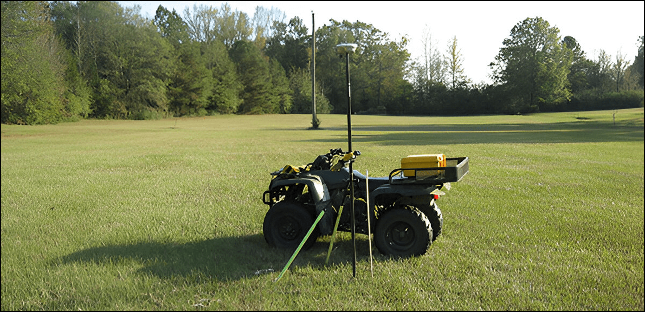 ATV on grassy field with surveying equipment.